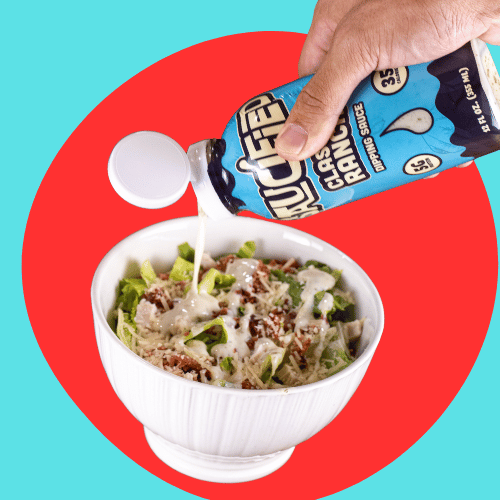 Hand pouring Classic Ranch dressing into a bowl of salad on a colorful background