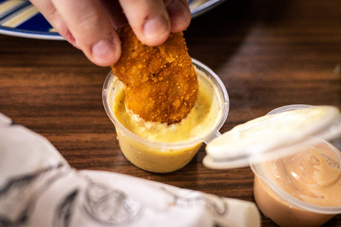 Crispy nugget being dipped into honey mustard protein sauce