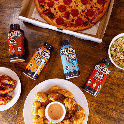 Assorted sauces on a table with a pizza and other food items.